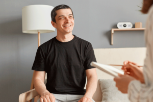 a young man smiles while talking with a therapist about addiction recovery for men