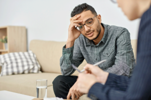 a young man listens to a therapist talk about benefits of men's rehab