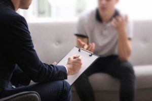 a man sits on the couch as he talks to a therapist at a xanax addiction treatment program