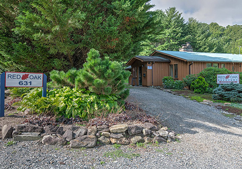 a cabin behind two signs. one that reads "Red Oak Recovery<sup>®</sup>" and another that reads "Red Oak 631"