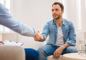 a young man in a benzo addiction treatment center shakes hands with a counselor