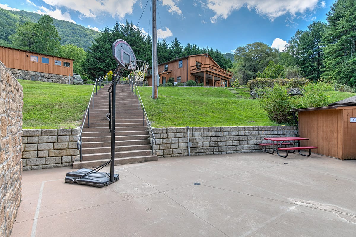 a basketball goal on a patio downhill from two cabins
