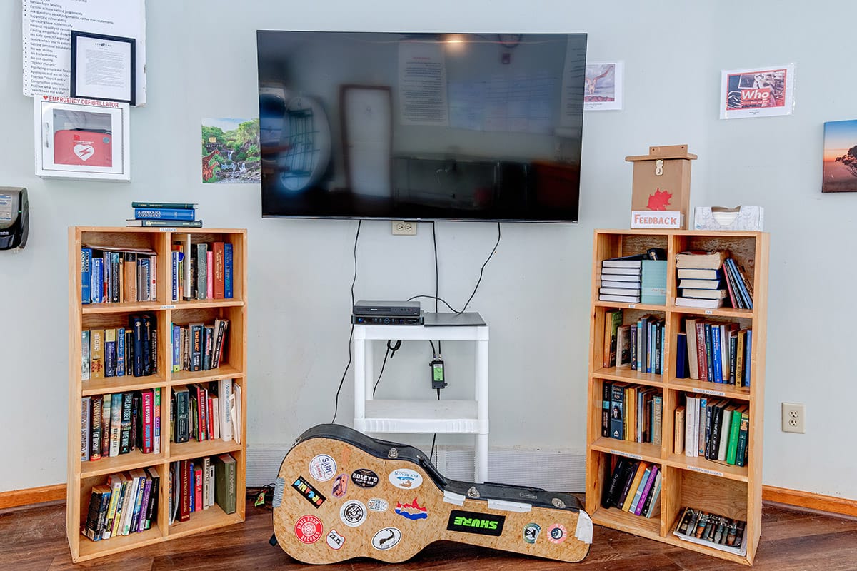 a television between two bookcases and a guitar case