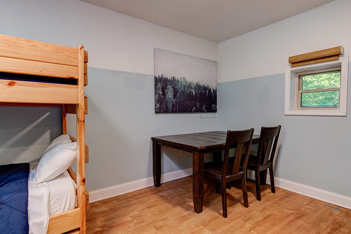 a table and two chairs in a room with bunk beds