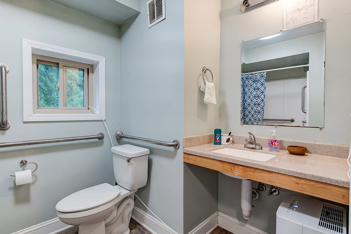 a clean bathroom with an accessible toilet, sink, and mirror