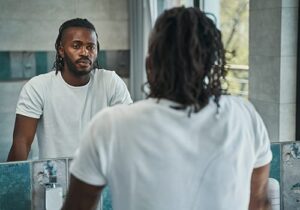 a young man stares in a mirror at an eating disorder treatment program