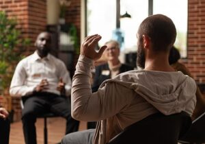 a group of young men in an opioid addiction treatment center listen to someone talk