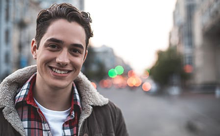 a young man smiles near a busy street