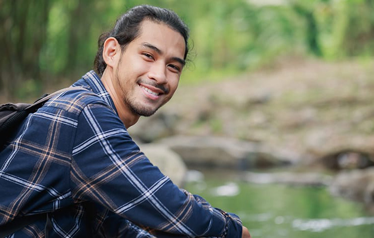 a young man smiles outdoors