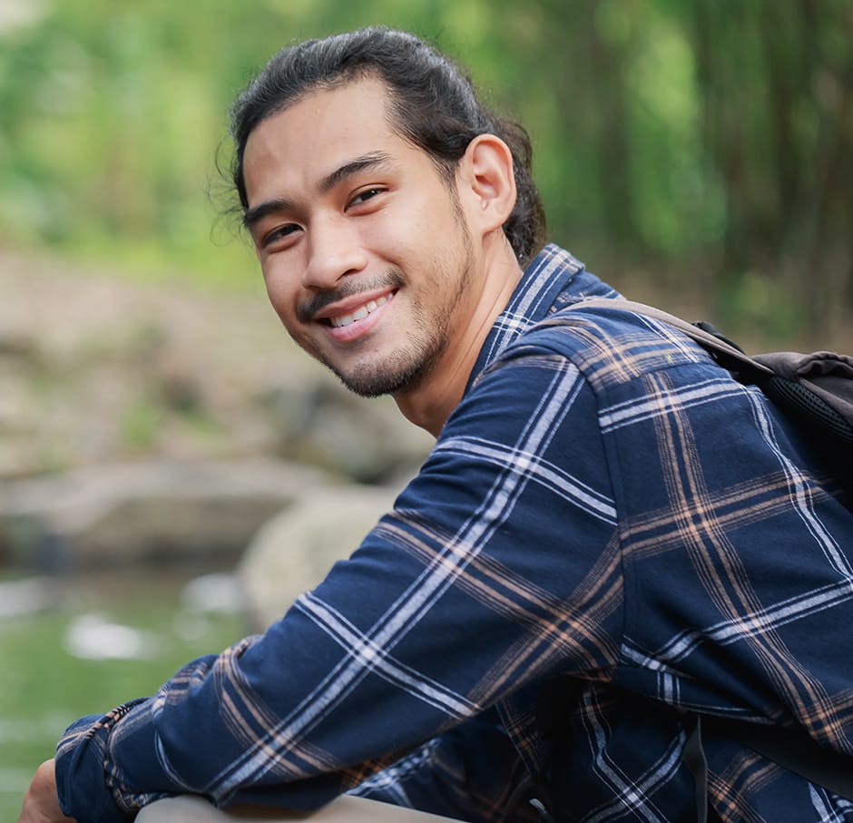 a young man smiles outdoors