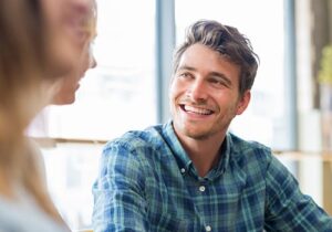 a man in a young men's rehab program smiles at a therapist in a group