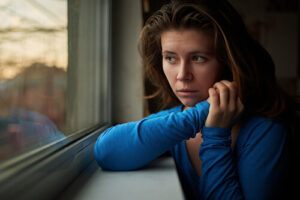 A woman stares out a window and wonders "Am I an alcoholic?"