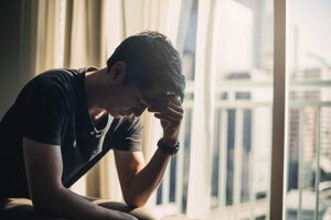 a young man sits in bed looking sad, potentially in need of a grief counseling program