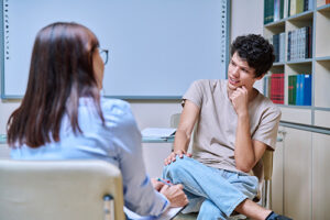 a young man talks to a counselor during psychotherapy for men