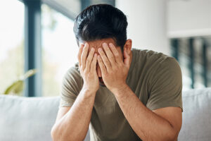 a young man in need of a trauma therapy program holds his head