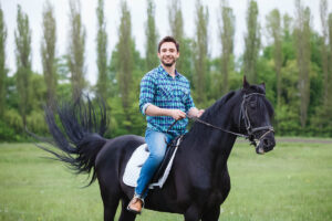 a young man rides a horse, exploring the benefits of equine therapy