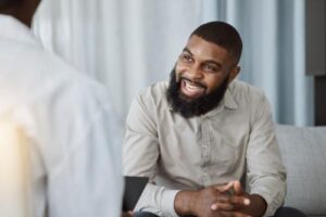 a young man smiles at a therapist during a 12-step recovery program