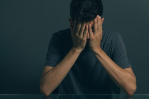 a man holds his face as he wonders "what is a trauma response?"